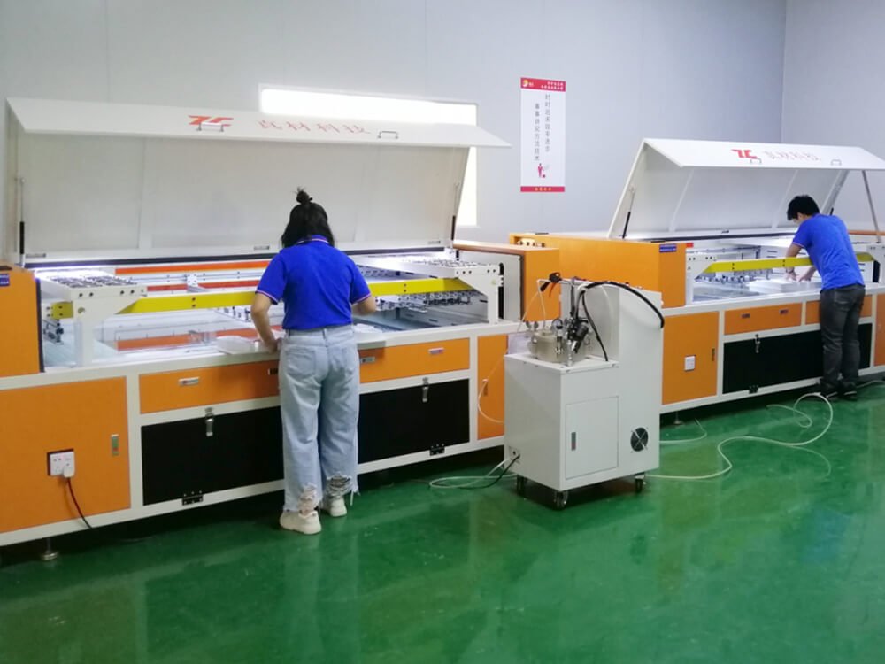 Two workers operating acrylic vacuum forming machines for light box manufacturing