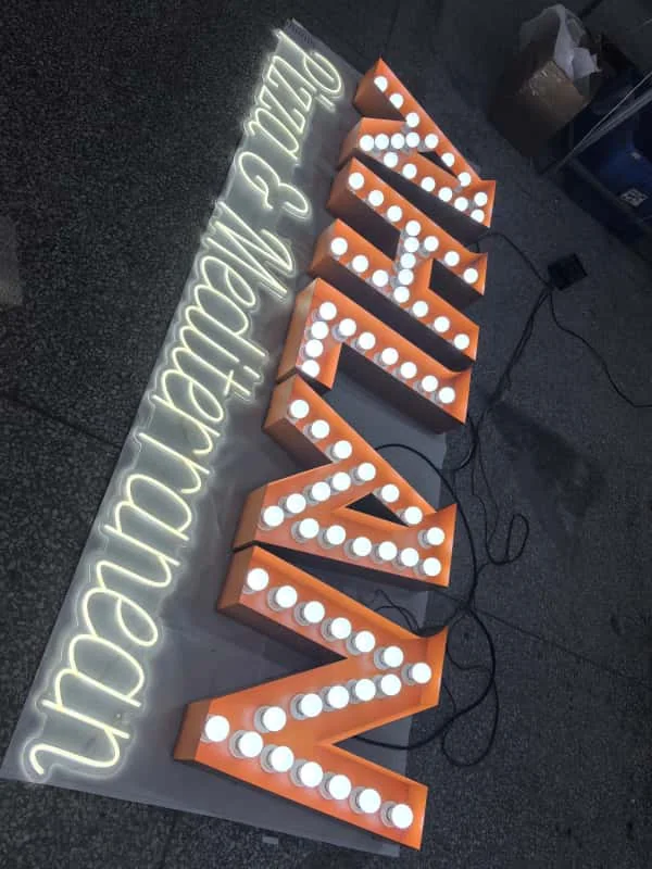 Vertical bulb-lit arrow sign with exposed dimensional letters