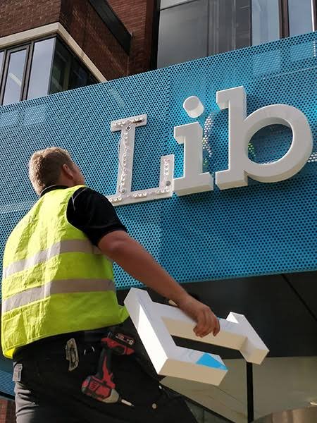 Aluminum sign letter installation Installer handling lightweight fabricated aluminum sign letters