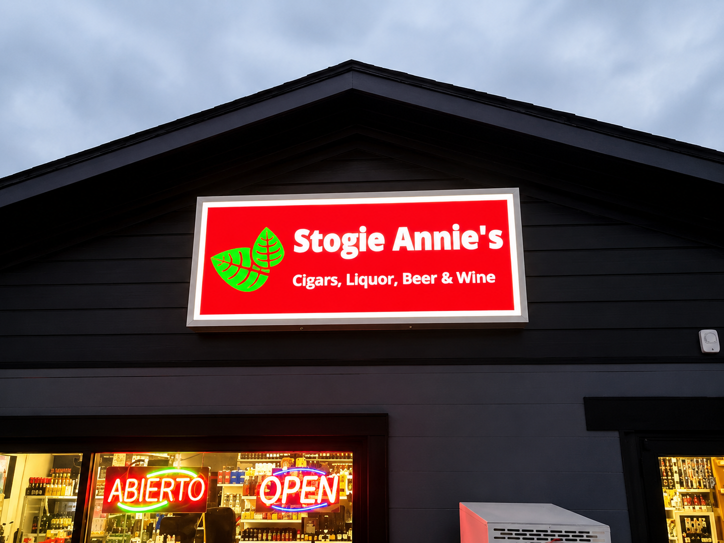 Commercial storefront showing an illuminated cabinet sign and neon window signs