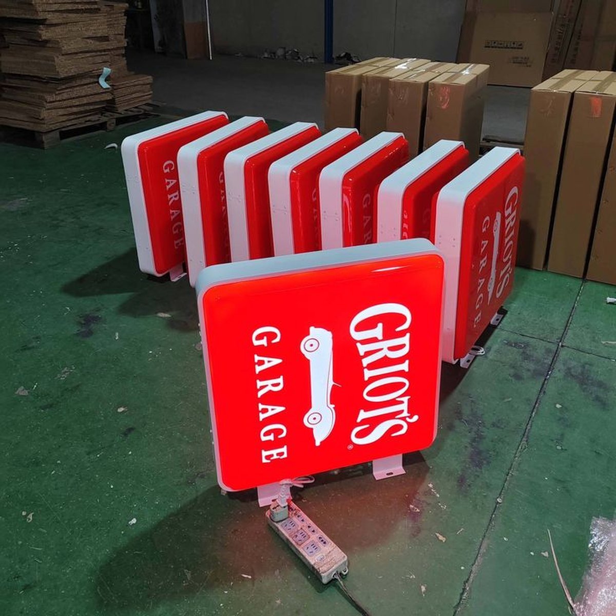 Multiple red CARAGE illuminated light boxes lined up on a workshop floor.