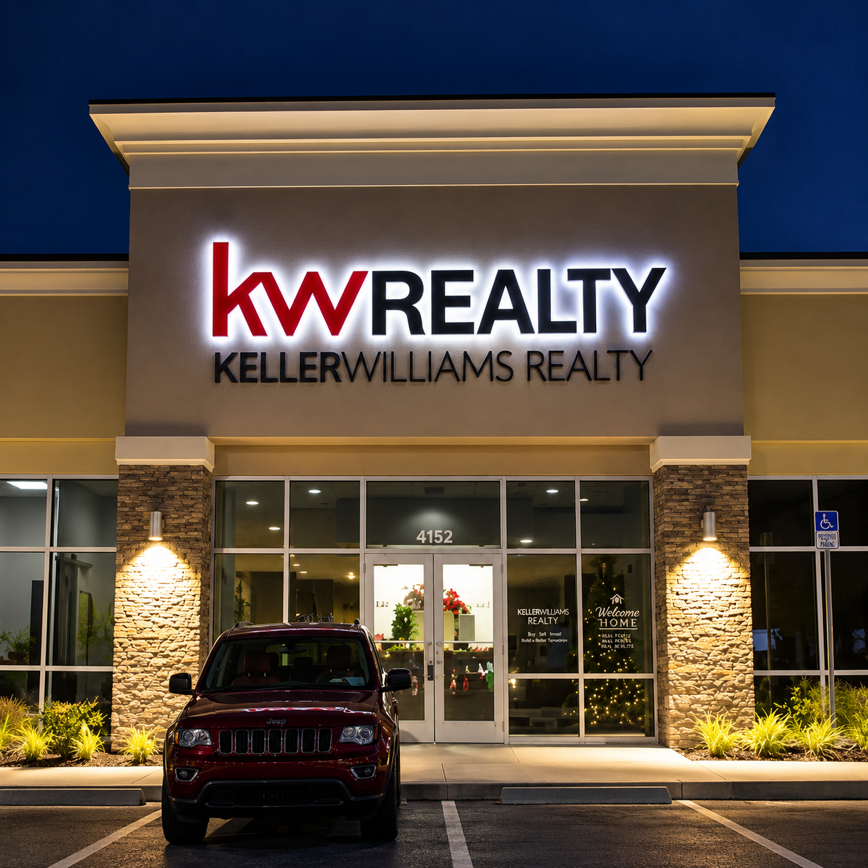 Illuminated Keller Williams Realty wall sign above a commercial entrance at night.