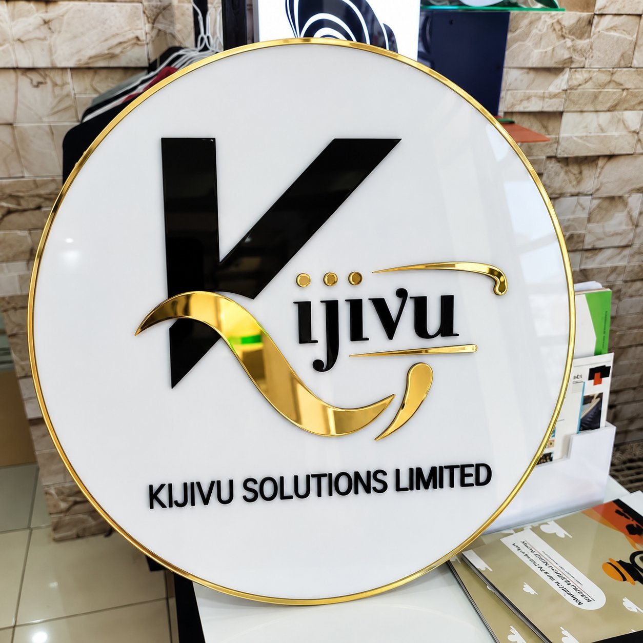 Front view of a finished circular acrylic sign with gold metal trim and acrylic letters.