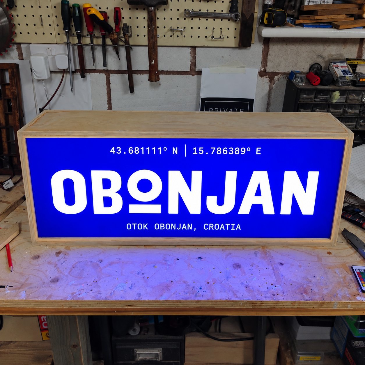 OBONJAN Croatia lightbox sign in a workshop, blue acrylic face on a wooden frame, pre-shipment.