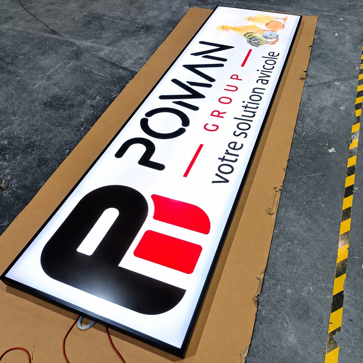 POMM/N GROUP lightbox sign with red and black brand mark, factory output on the production floor.