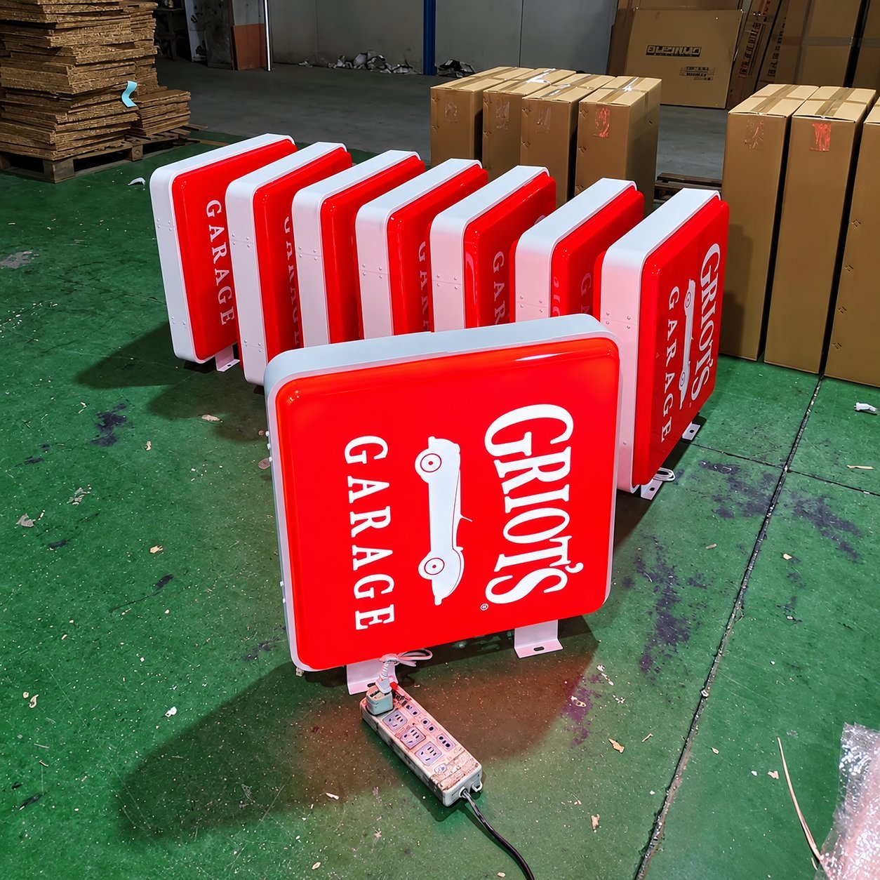 CRIOTO'S Garage illuminated signs lined up in the factory, showing how a brand mark stays consistent across multiple identical signs.