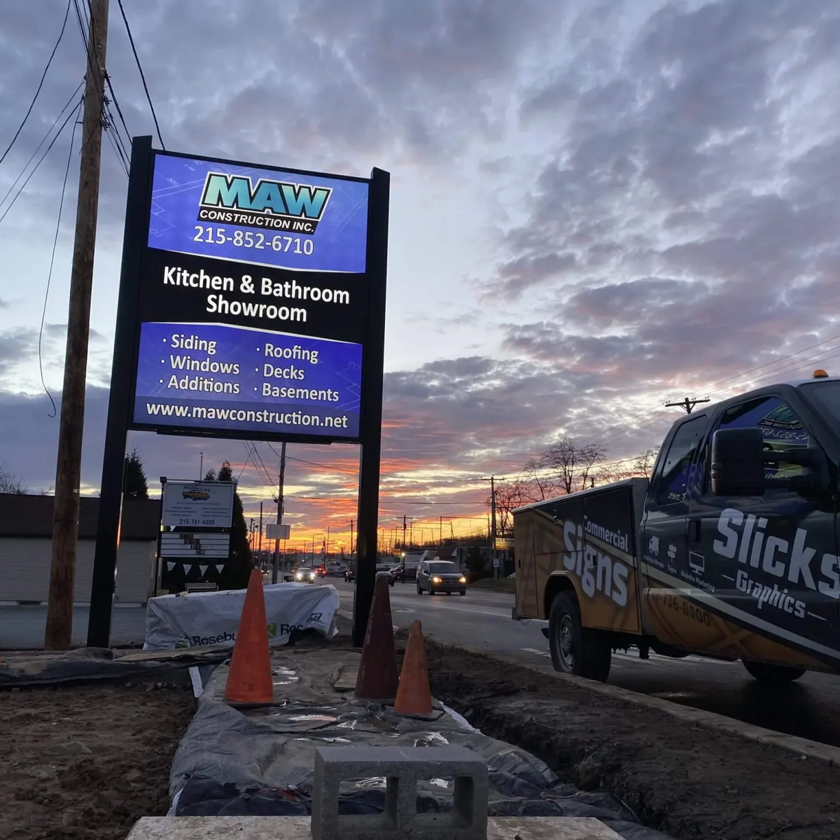 Two-post commercial pylon sign beside a service truck at dusk.