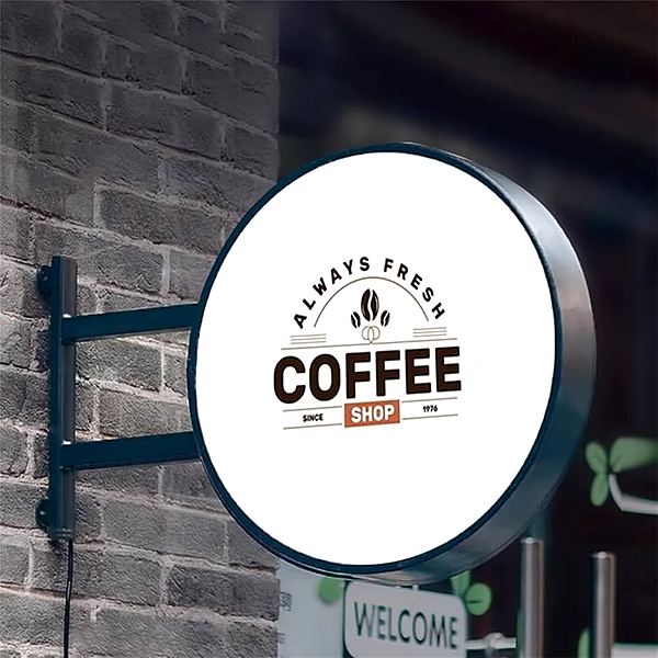 Round double-sided illuminated light box storefront sign mounted on a brick wall