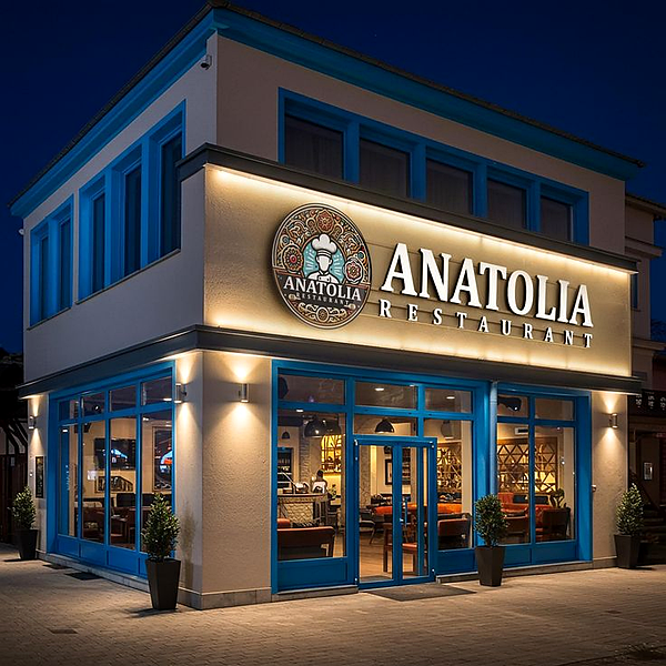 Illuminated restaurant storefront sign with logo medallion on a building corner