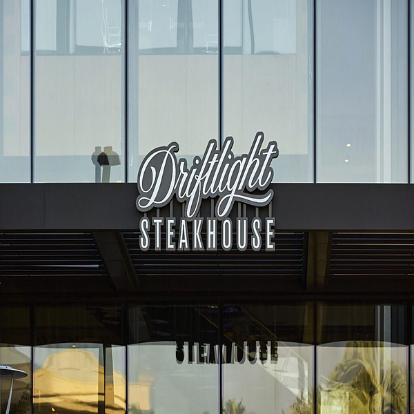 Hospitality storefront sign with script lettering on a glass curtain wall facade