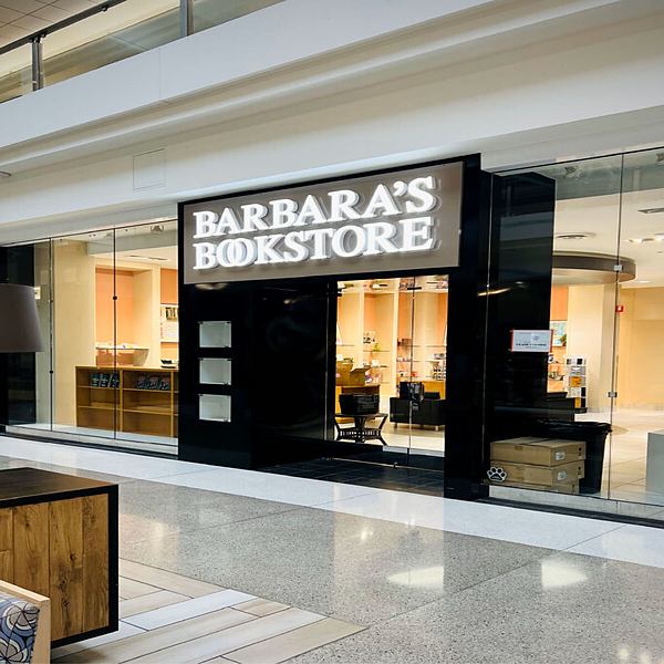 Illuminated light box storefront sign inside a shopping mall corridor