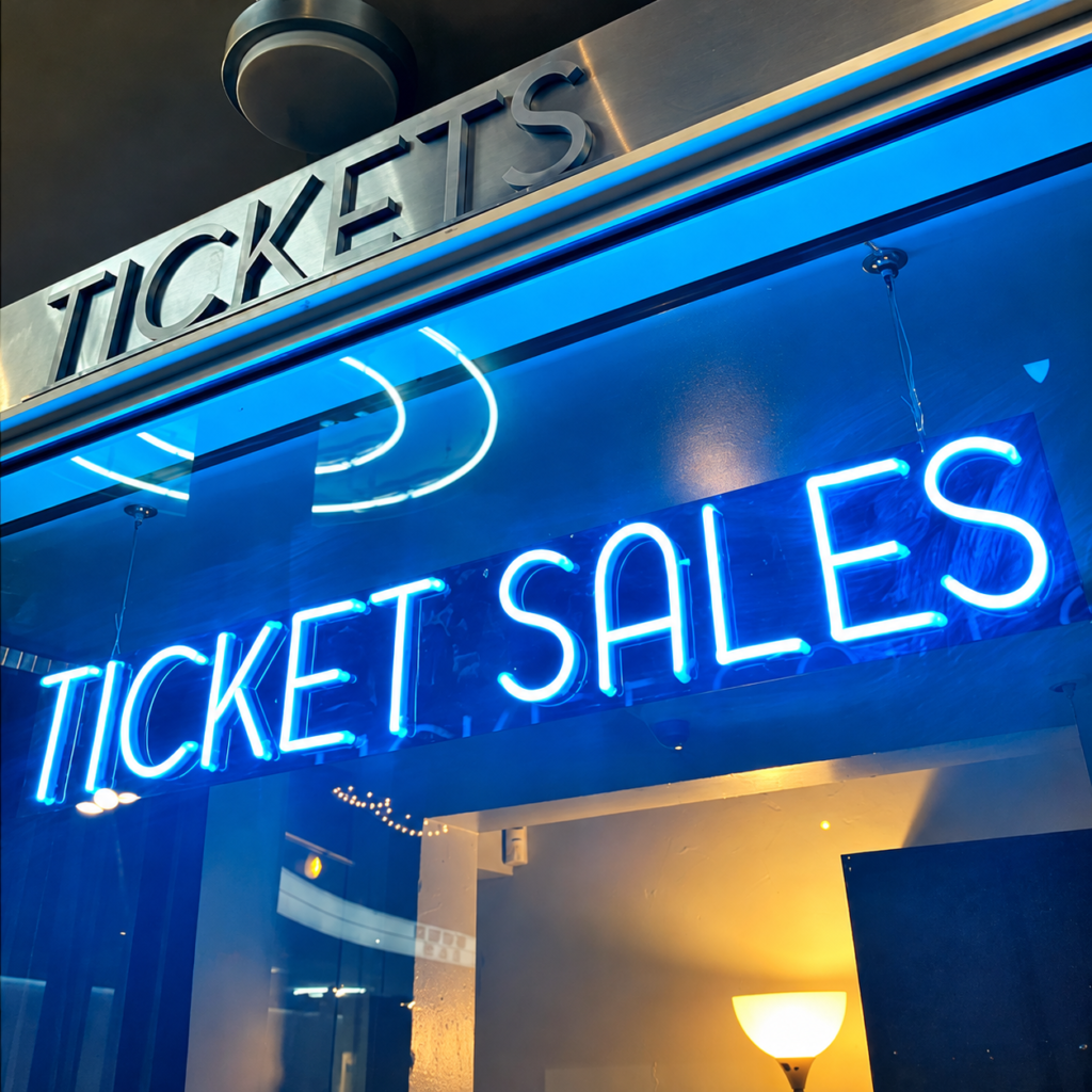 Blue neon illuminated storefront sign for a ticket sales counter